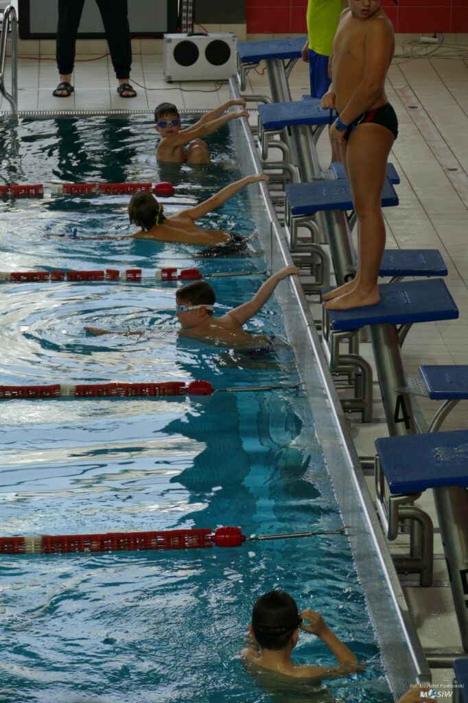 Młodzi zawodnicy na starcie zawodów pływackich.